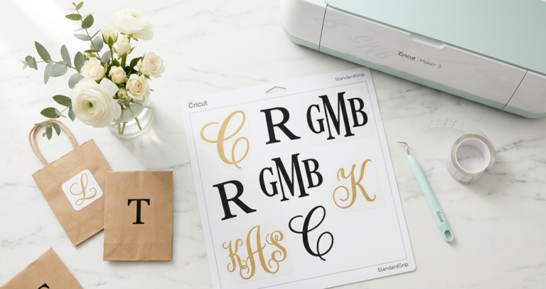Monogram SVG letters in elegant fonts cut on Cricut machine displayed on white marble surface with craft tools
